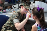 A Marine from the Marine Cryptologic Support Battalion paints one of many faces at the Armed Forces & National Police Celebration. The Marines also allowed visitors to dress in combat gear.