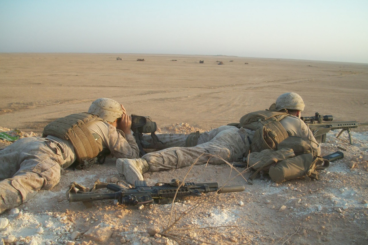Two Marines in the prone position engage simulated targets.