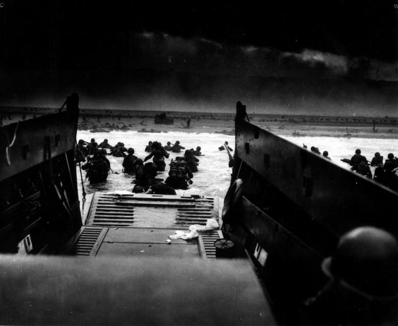 Soldiers with the U.S. Army 1st Infantry Division disembark from a Coast Guard landing craft while under machine gun fire from German army fortifications on June 6, 1944, on Omaha Beach in Normandy, France. Omaha beach was the most heavily defended of the beaches in Normandy. (U.S. Coast Guard photo by Chief Petty Officer Robert F. Sargent)