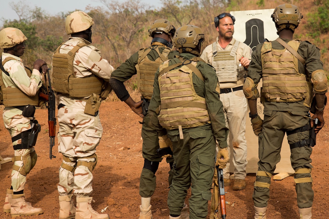 A soldier instructs others at a firing range.