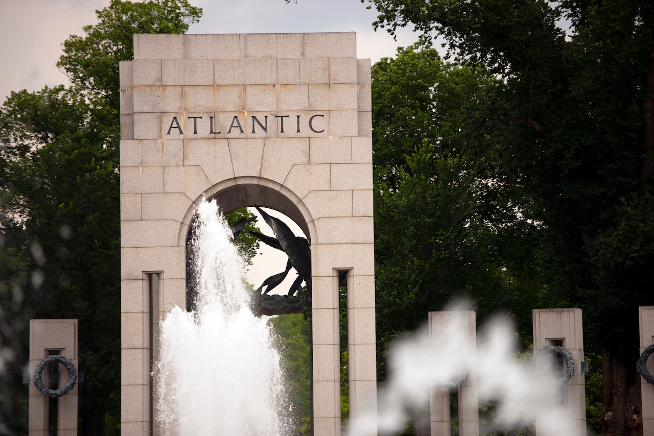 Water fountains appear in front of a stone arch that bears the word “Atlantic.”