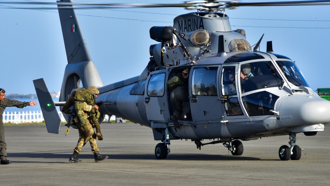 A British Army soldier carries a simulated casualty to a Mexican Navy helicopter.