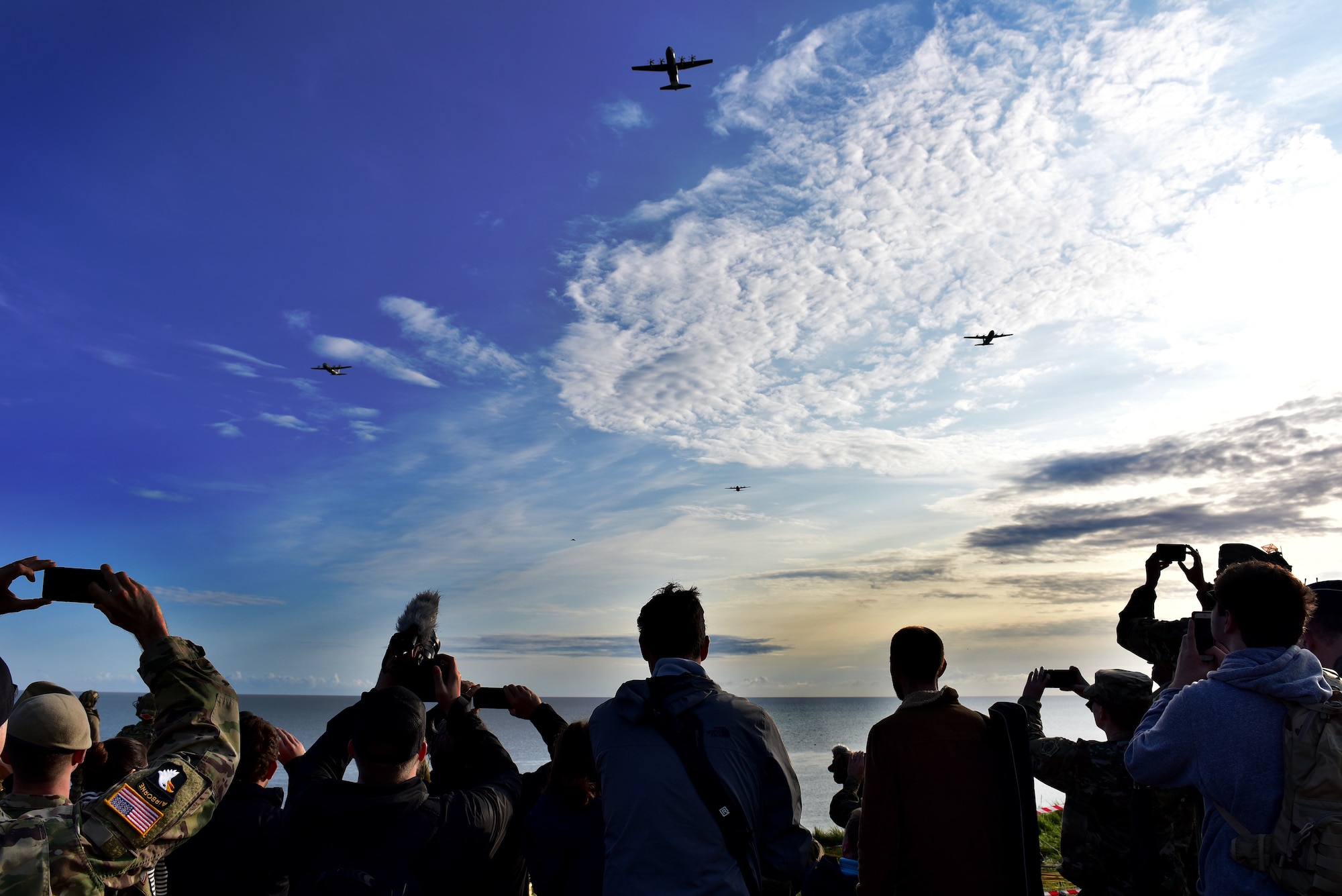 A C-130J flies over a crowd