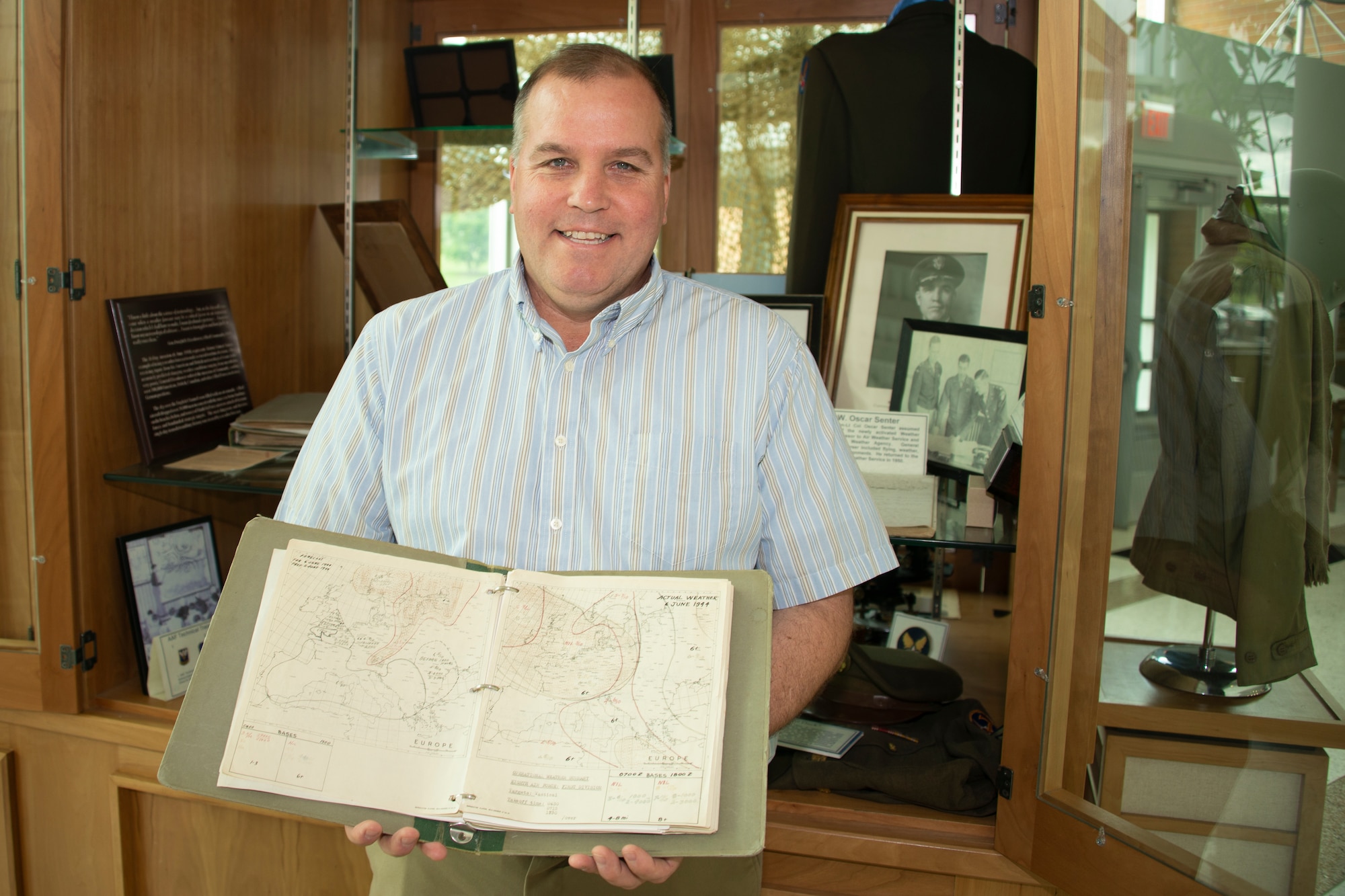 Dr. Kent Sieg, 557th Weather Wing historian, shows an 8th Air Force weather map depicting the predicted and actual weather conditions for Europe for June 6, 1944, at the 557th Weather Wing headquarters building, Offutt Air Force Base, Nebraska, May 29, 2019. Originally scheduled for June 5, 1944, forecasts for bad weather led D-Day planners to delay the invasion of Europe to June 6, 1944. (U.S. Air Force photo by Paul Shirk)
