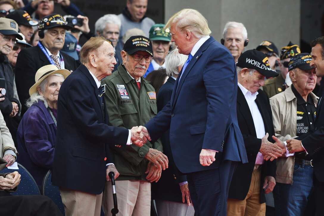 President Donald J. Trump shakes hands with a veteran as others look on.