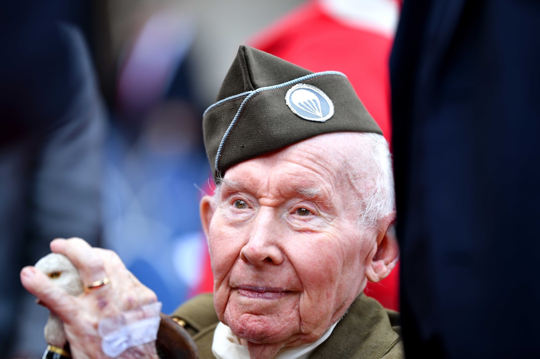 A veteran wearing a uniform sits and holds a cane.