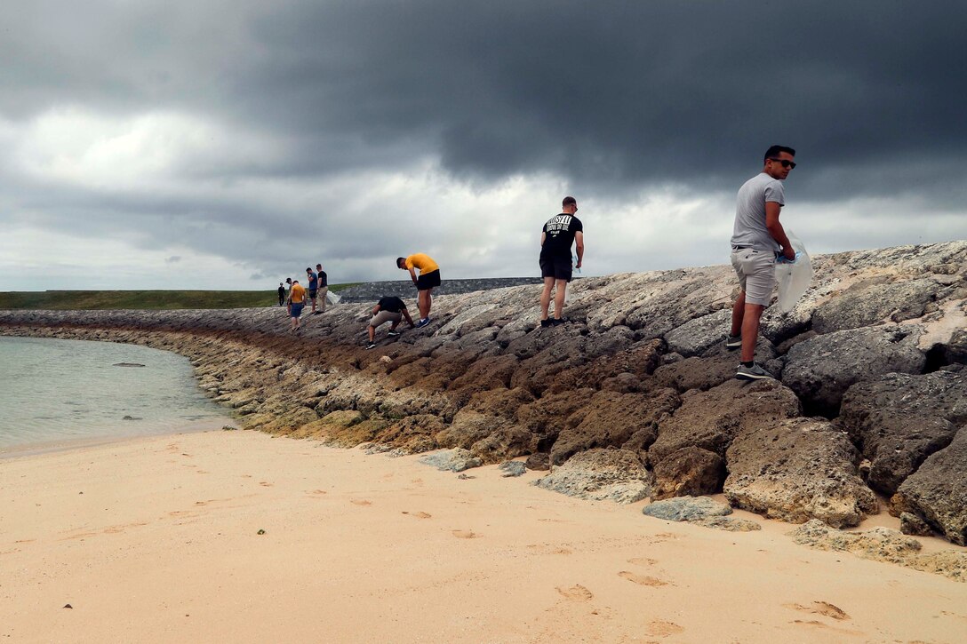 沖縄県宜野湾市にあるトロピカルビーチで清掃活動を行った在日米海兵隊所属の隊員らが防波堤沿いのゴミを拾っています。第３歯科大隊の隊員とその家族が金曜日、トロピカルビーチで清掃活動を行いました。