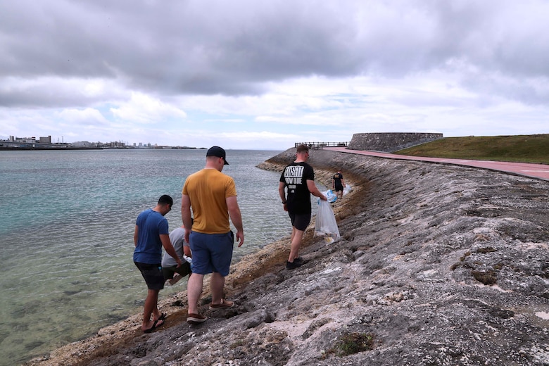 沖縄県宜野湾市にあるトロピカルビーチで清掃活動を行った在日米海兵隊所属の隊員らが防波堤沿いのゴミを拾っています。第３歯科大隊の隊員とその家族が金曜日、トロピカルビーチで清掃活動を行いました。