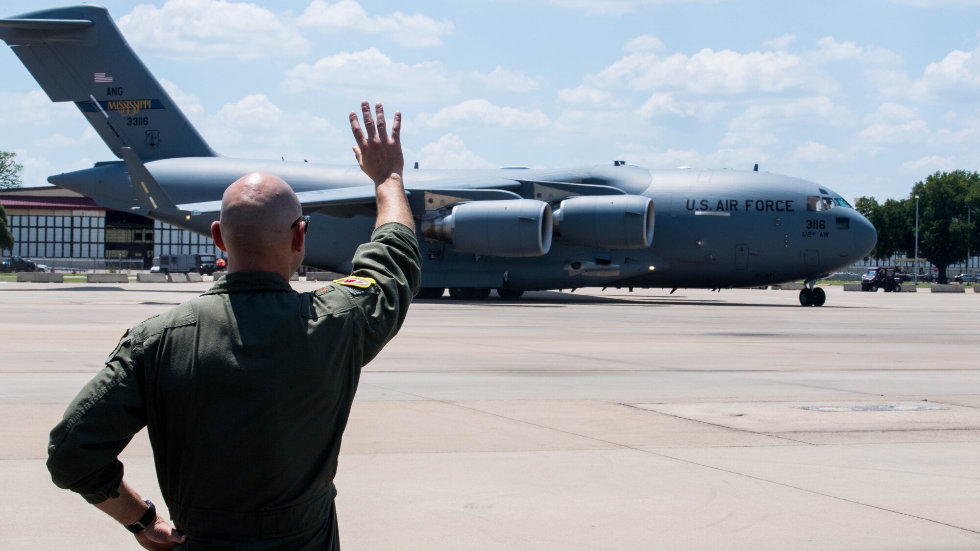 Maj. John R. Blankenship, a B-52 Stratofortress pilot with the 96th Bomb Squadron, waves to his wife Maj. Natasha E. Blankenship, a C-17 Globemaster III pilot with the 183rd Airlift Squadron in Jackson, Mississippi, as she lands a C-17 as apart of the Barksdale Defenders of Liberty Air Show at Barksdale Air Force Base, La., May 16, 2019. Natasha Blankenship is a prior active duty pilot who now flies for the Mississippi Air National Guard. (U.S. Air Force photo by Airman Jacob B. Wrightsman)