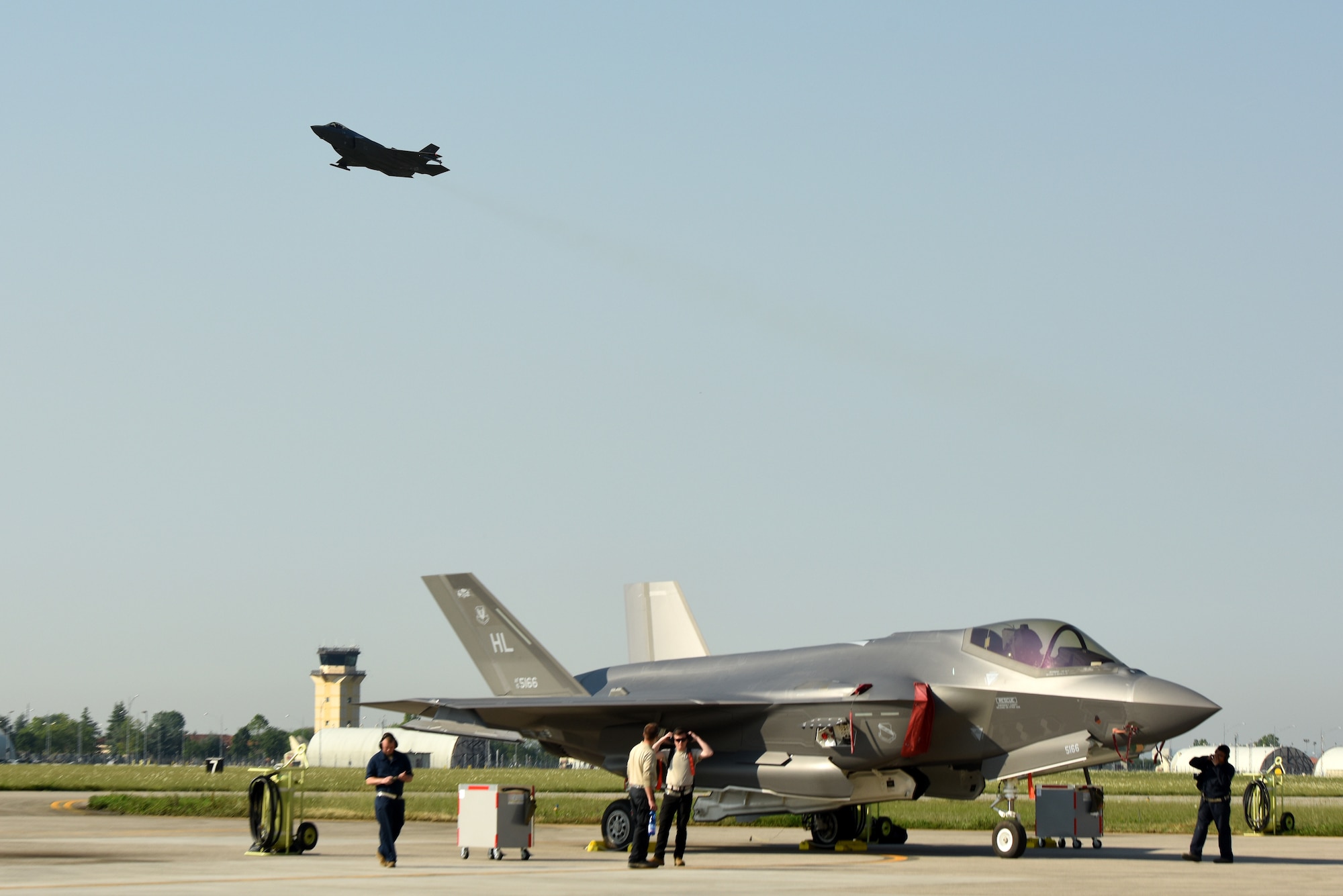 An F-35A Lightning II fighter jet sits on the flightline while another F-35A takes off during Astral Knight 2019 June 3, 2019, at Aviano Air Base, Italy. The F-35A contains state-of-the-art tactical data links that provide secure sharing of data among its flight members as well as other airborne, surface and ground-based platforms. The Airmen are deployed from the active duty 388th and Reserve 419th Fighter Wings at Hill Air Force Base, Utah. (U.S. Air Force photo by Tech. Sgt. Jim Araos)