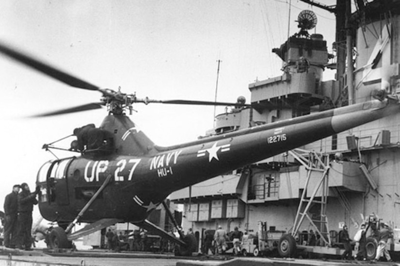 A black and white photograph of a military helicopter on board a ship.