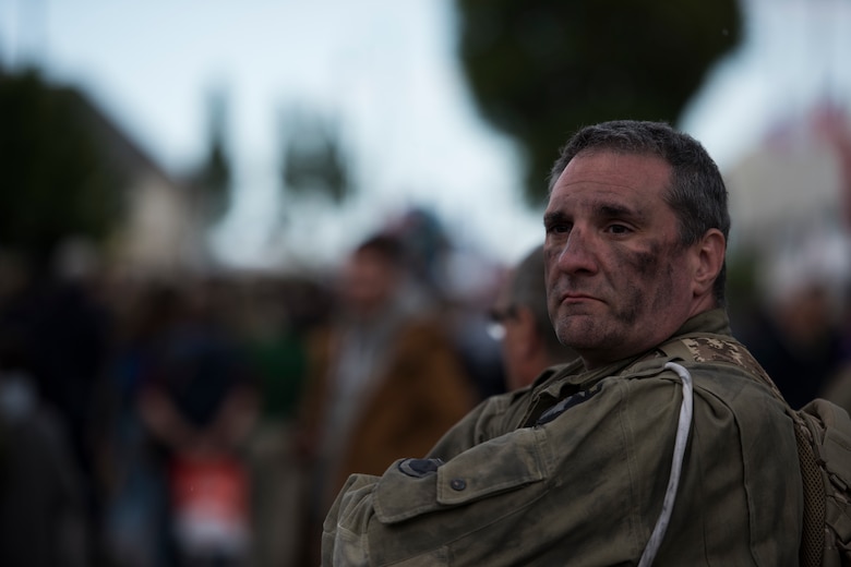 A U.S. spectator, dressed in a WWII-era uniform, looks on at the activity and people around him in the village square of Sainte-Mère-Église, France, June 6, 2019. This year marks the 75th anniversary of D-Day and the liberation of Normandy. The events held in Sainte-Mère-Église were just a few of 55 events held throughout 40 different French communities honoring those that paid the ultimate sacrifice on June 6, 1944. (U.S. Air Force photo by Senior Airman Kristof J. Rixmann)