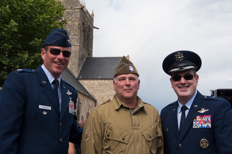 U.S. Air Force Brig. Gen. Mark August, 86th Airlift Wing commander, and Col. Joseph Wenckus, 86th Airlift Wing vice commander, pose with a U.S. military veteran dressed in a WWII-era uniform in honor of the 75th anniversary of D-Day in Sainte-Mère-Église, France, June 6, 2019. Behind them is the church of which U.S. Army Private John Steele’s parachute snagged on the tower during the D-Day invasion. Steele would be captured by German forces but would escape captivity four days later and return with the 82nd Airborne Division. (U.S. Air Force photo by Senior Airman Kristof J. Rixmann)