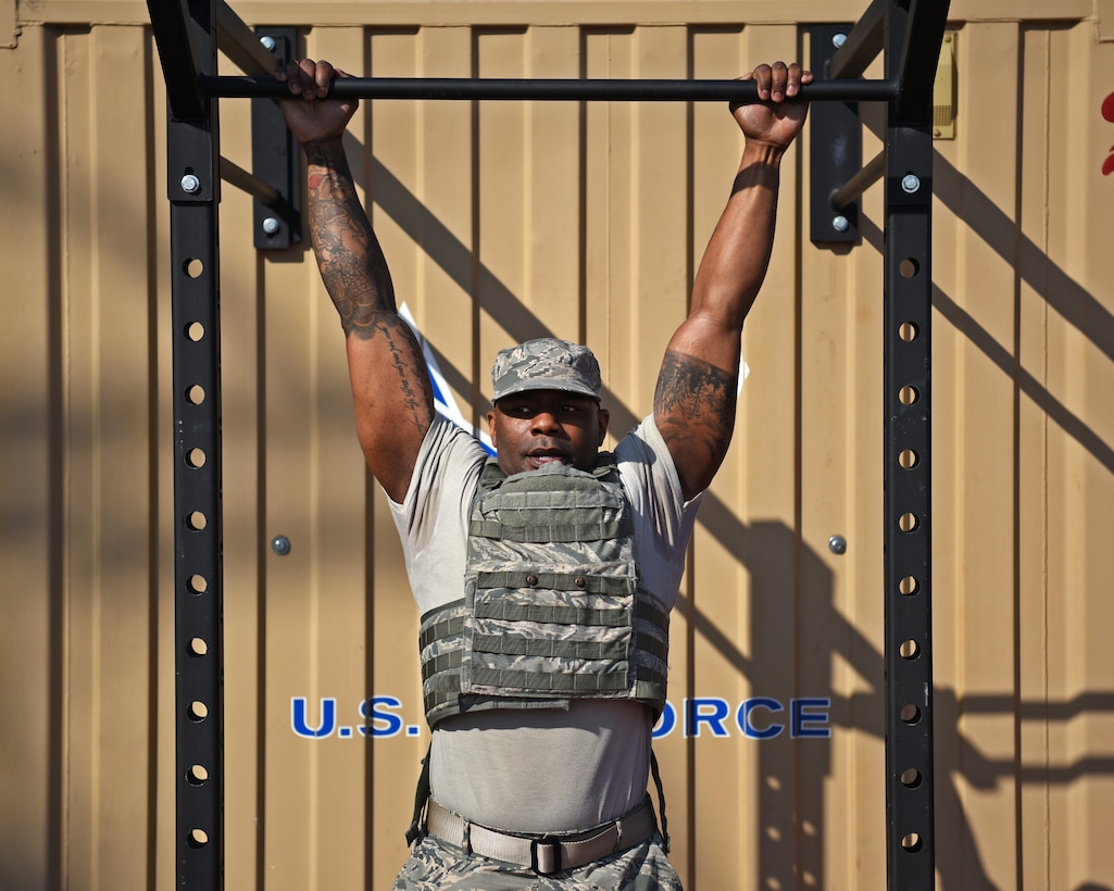 A first sergeant hangs from a pull-up bar
