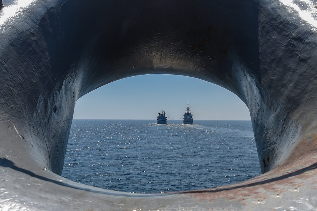 A tanker replenishes another ship at sea.