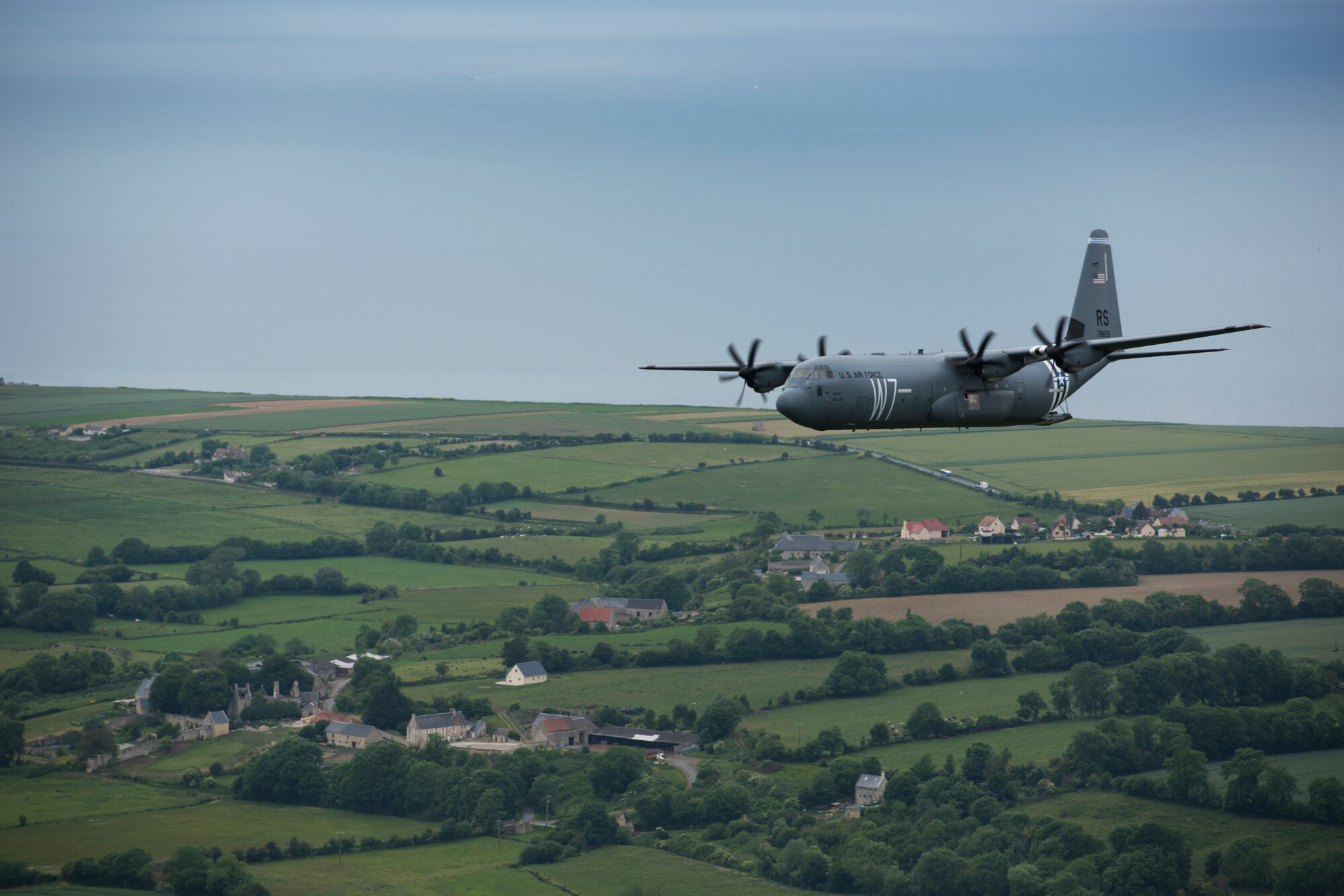 A C-130J Super Hercules, belonging to the 37th Airlift Squadron on Ramstein Air Base, bearing the Whiskey-7 marker, flies as part of a four-ship formation over the coast of Normandy, France, June 5, 2019. The 37th Troop Carrier Squadron bore the W7 identifier during D-Day as their pilots dropped airborne infantrymen on intended drop zones. As their legacy squadron, the 37th AS bears the W7 identifier in 2019 to pay homage to the 37th TCS and the sacrifices they made on D-Day. (U.S. Air Force photo by Senior Airman Kristof J. Rixmann)