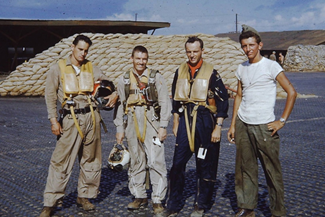 Four airmen pose for a picture on an air base.