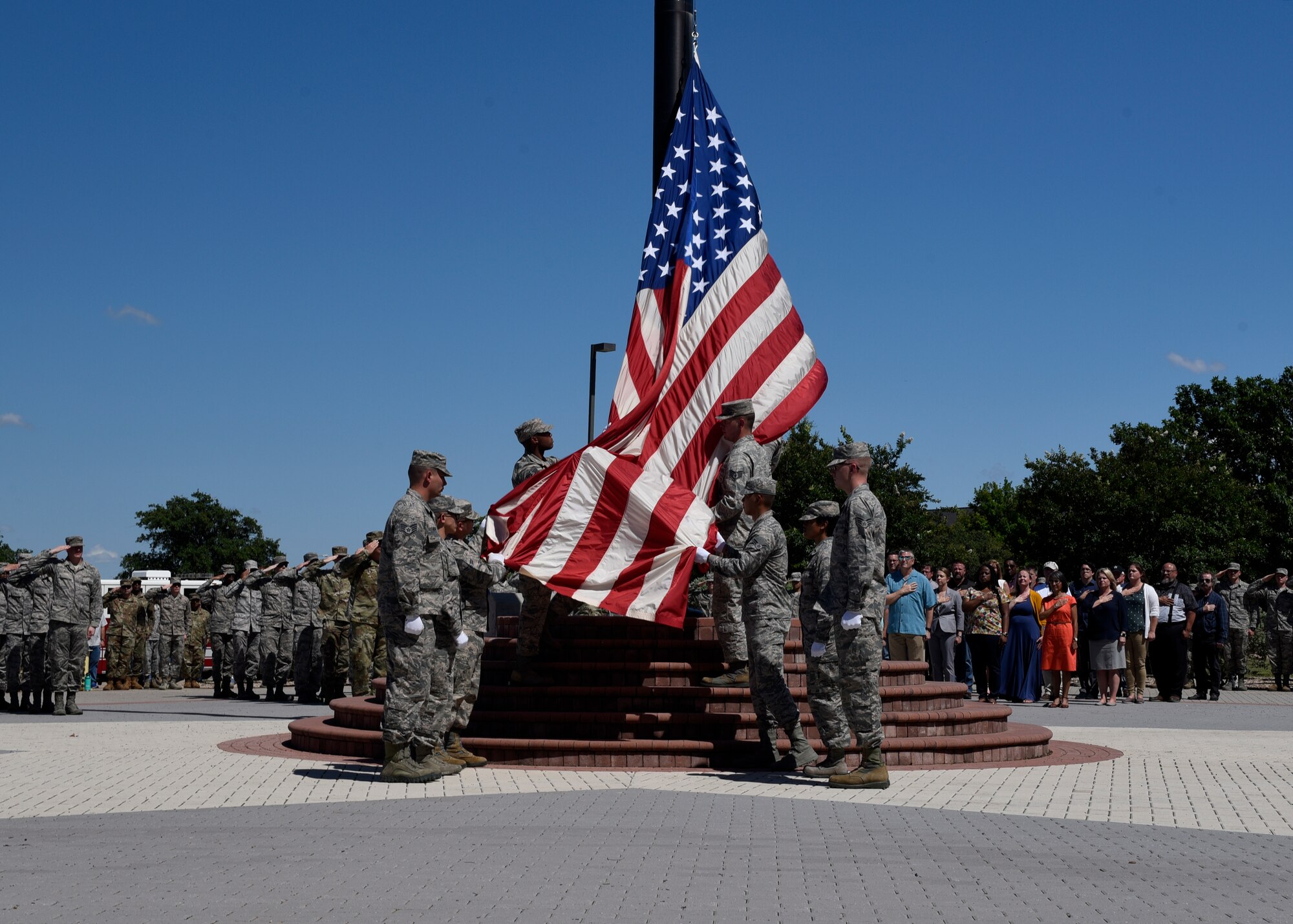 Goodfellow Air Force Base color guard members lower the flag during a special D-Day retreat at the Norma Brown building here, June 6, 2019.  Civic leaders and Goodfellow members were invited out to join in the remembrance and the fly over by the C-130J Super Hercules. (U.S. Air Force photo by Airman 1st Class Zachary Chapman/Released)