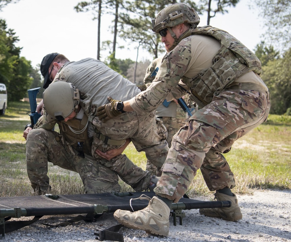Service members help a simulated victim during an exercise.