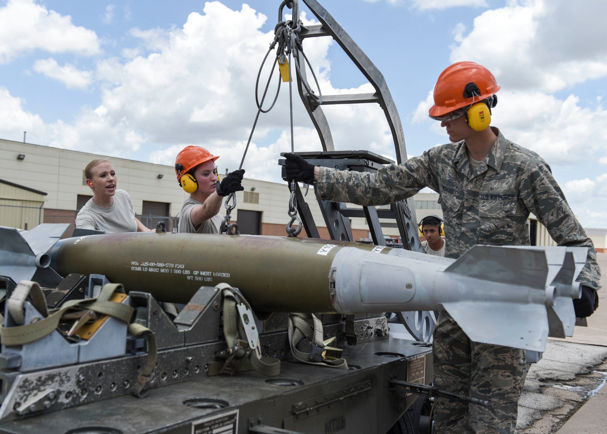 363rd Training Squadron munitions apprentice course students attach a Mark 82 training bomb to an MJ-1 ammunition loader while their instructor, left, supervises at Sheppard Air Force Base, Texas, June 7, 2019. The students actually built the bombs before and are now performing a crossload, which moves the bombs from one trailer to another. A crossload is performed when a trailer is either scheduled for maintenance or due to mission requirements must be moved. (U.S. Air Force photo by Senior Airman Ilyana A. Escalona)