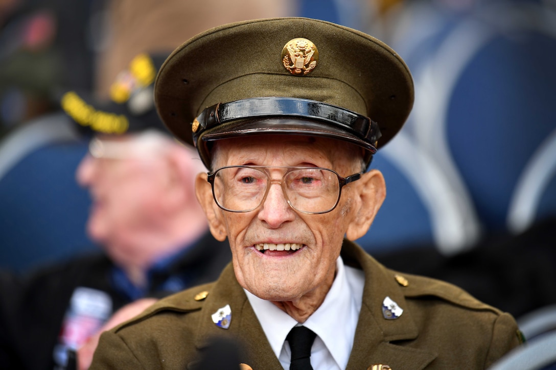 A veteran wearing a uniform smiles in a crowd of people.