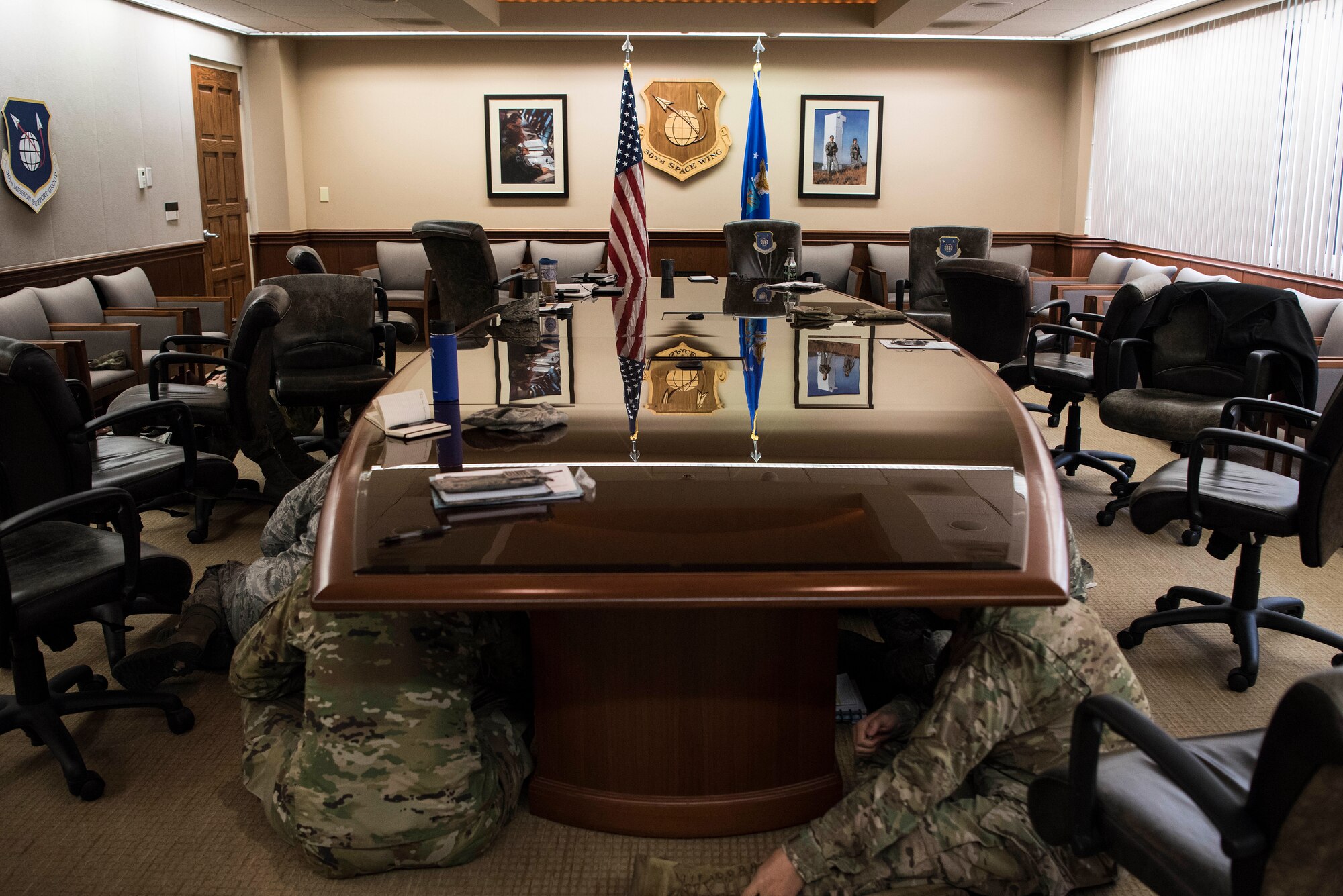 30th Space Wing members take shelter under a table during a base-wide earthquake exercise June 5, 2019, at Vandenberg Air Force Base, Calif. In the event of an earthquake, individuals should hide under and hold onto a desk or table or stand against an interior wall until the shaking has subsided. (U.S. Air Force photo by Airman 1st Class Hanah Abercrombie)