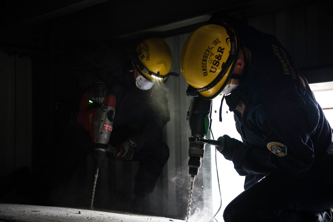 Richard Strange and Luke McIntosh, 30th Civil Engineer Squadron firefighters, drill through concrete to rescue members in a trapped car during a base-wide earthquake exercise June 5, 2019, at Vandenberg Air Force Base, Calif. The exercise tested unit’s readiness and ability to perform their duties in the face of natural disaster. (U.S. Air Force photo by Airman 1st Class Hanah Abercrombie)