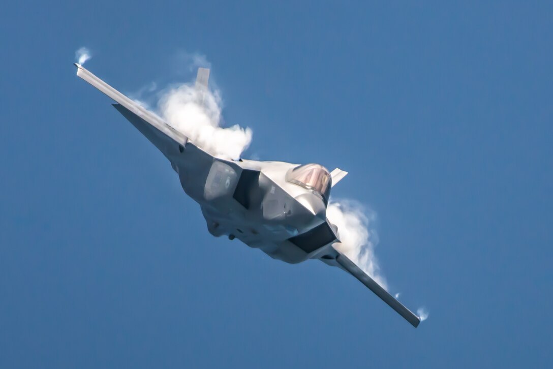 A fighter aircraft flies against a clear blue sky.