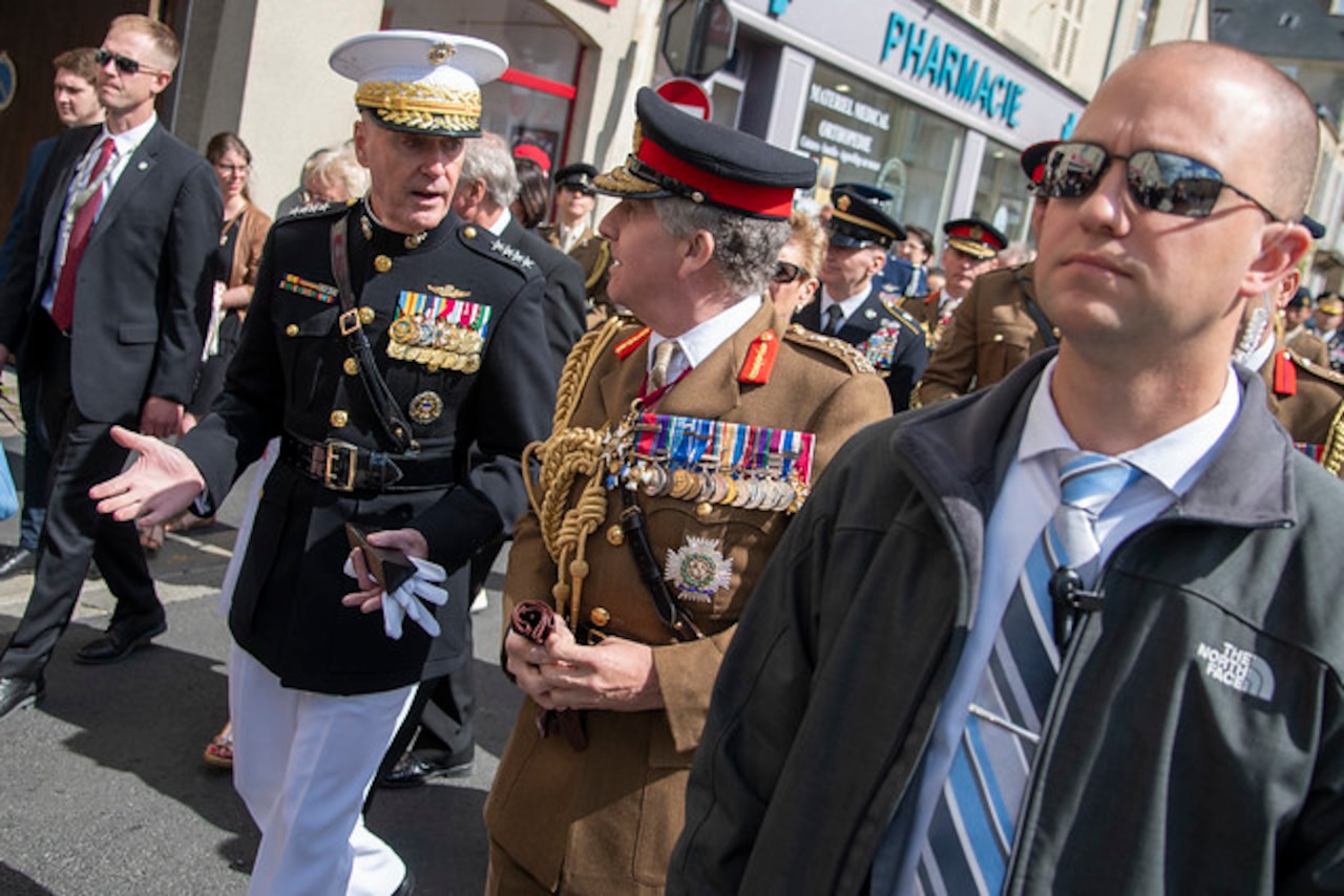 Senior military leaders speak to each other in French street.