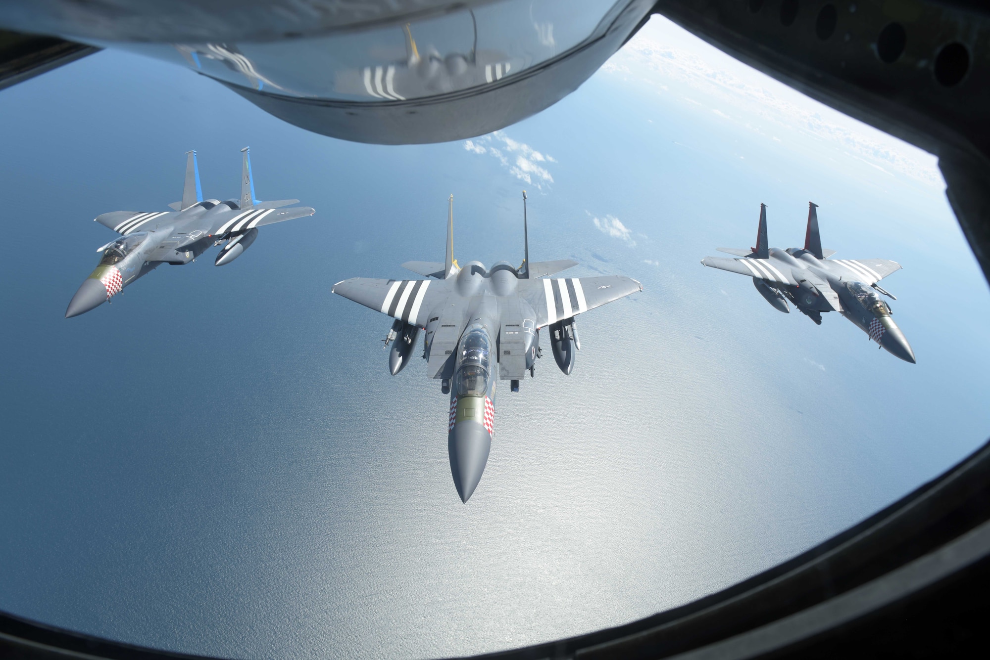 Three U.S. Air Force F-15s, assigned to the 48th Fighter Squadron at RAF Lakenheath, England, fly in formation behind a U.S. Air Force KC-135 Stratotanker off the Southern coast of England, June 6, 2019. The F-15s were painted with heritage markings in honor of the 75th anniversary of D-Day. As we commemorate D-Day 75, U.S. forces in Europe remain committed to collective defense and cooperative security alongside European allies and partners. (U.S. Air Force photo by Senior Airman Benjamin Cooper)
