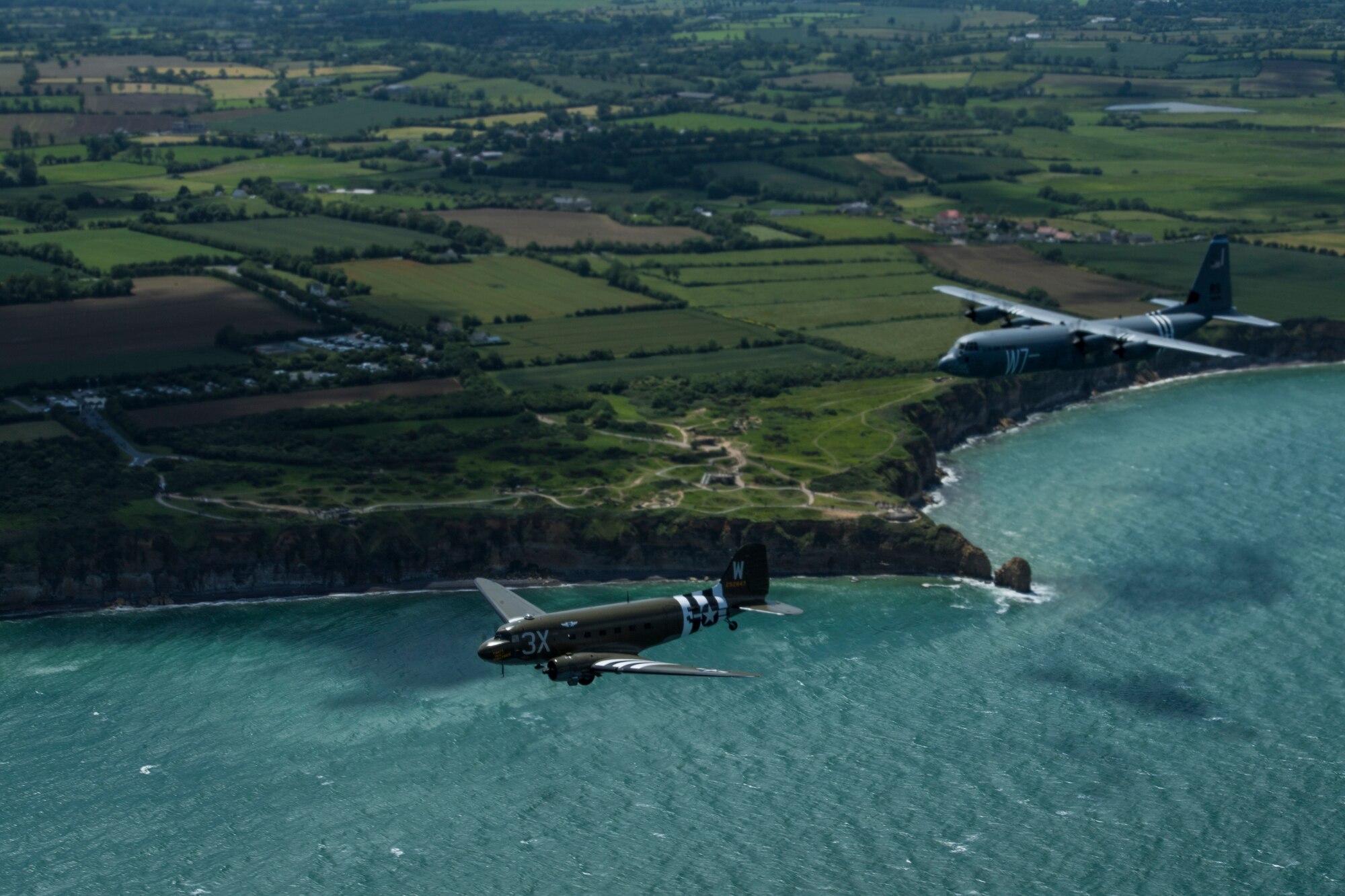 A Douglas C-47 Dakota, nicknamed “That’s All Brother”, flies with a U.S. Air Force C-130J Super Hercules, assigned to the 37th Airlift Squadron, Ramstein Air Base, Germany, over Pointe-du-Hoc, France, June 8, 2019. The 37th Troop Carrier Squadron, the legacy squadron to the 37th AS, wore the “W7” or “Whiskey 7” markings during Operation Neptune, June 6, 1944. “That’s All Brother” flew operations during the invasion of Normandy. (U.S. Air Force photo by Senior Airman Devin M. Rumbaugh)