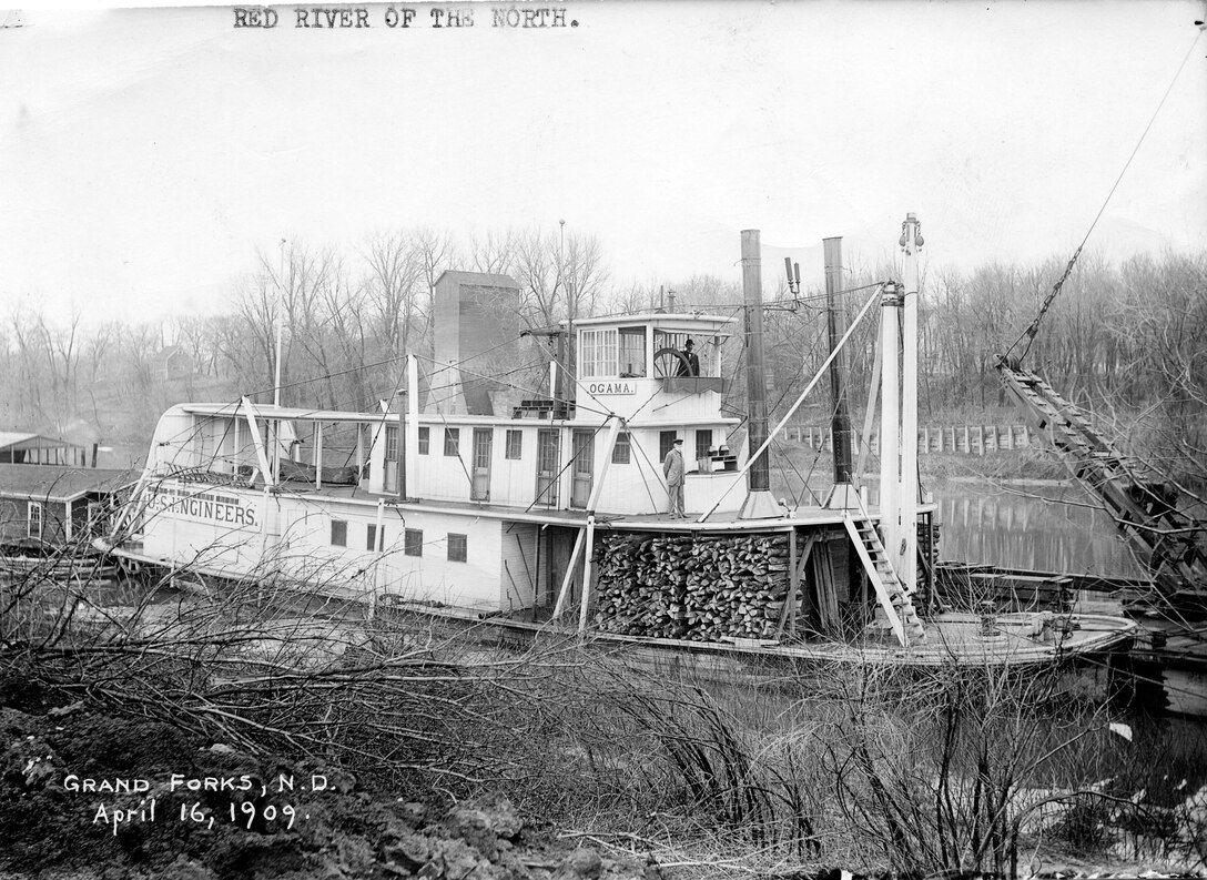 steamer with wood on deck in narrow river
