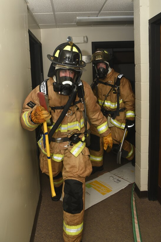 Airman 1st Class Arthur Punton leads Staff Sgt. Tyler Vandevelde, both fire fighters in the 119th Civil Engineer Squadron, as they conduct a search for victims through a smoky hallway following a simulated enemy attack during a training exercise at the North Dakota Air National Guard Base, Fargo, N.D., June 8, 2019.