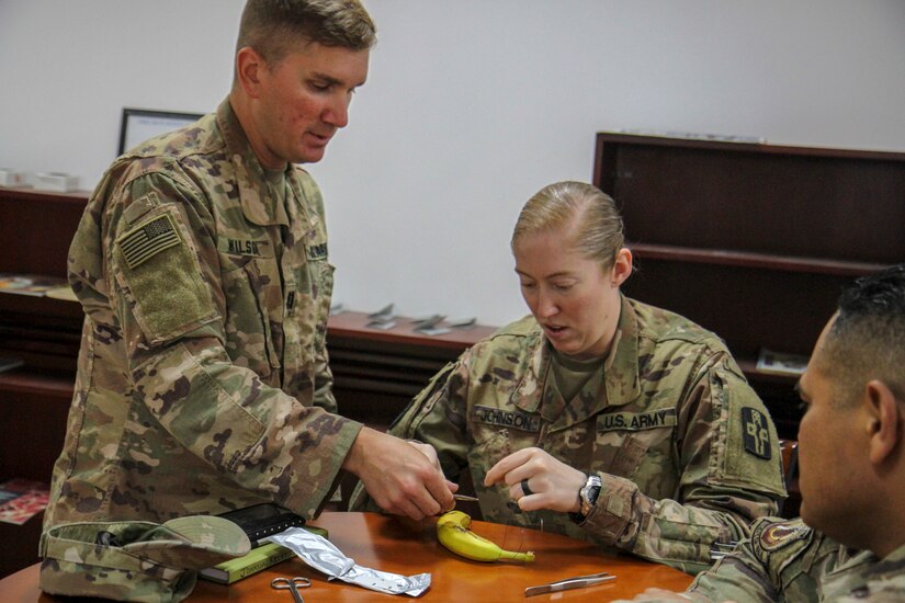 Army Capt. Michael Wilson, left, veterinarian, 719th Medical Detachment Veterinary Service Support, instructs Sgt. Kristie Johnson, supply sergeant, 354th Medical Company (Logistics), on how to tie a suture during training at Camp As Sayliyah, Qatar, May 31, 2019. Service members attending the training learned first aid and suturing techniques to better care for military working dogs if they were to be injured.