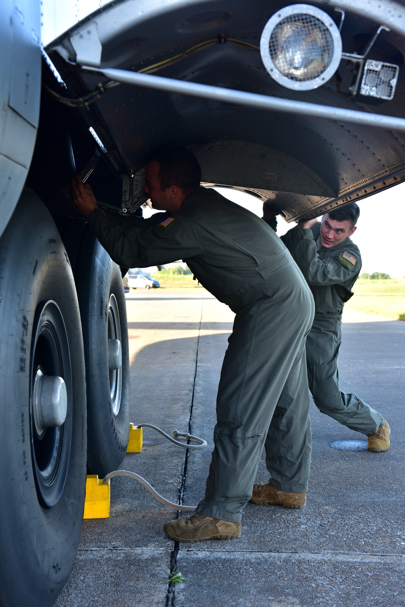 Two Airmen inspect the tire of a C-130J