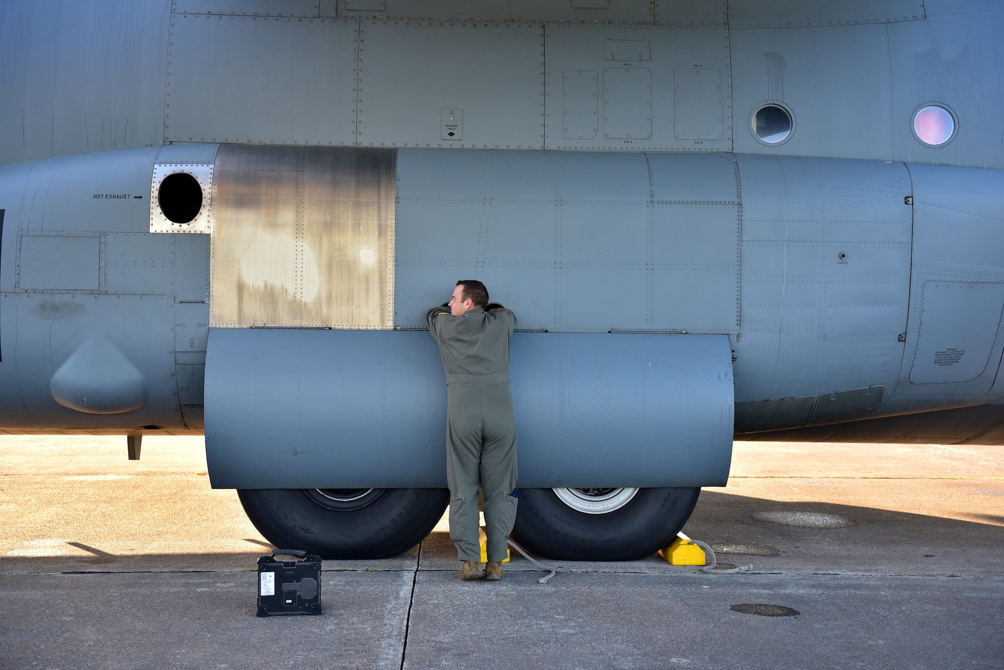 An Airman inspects the tire of a C-130J