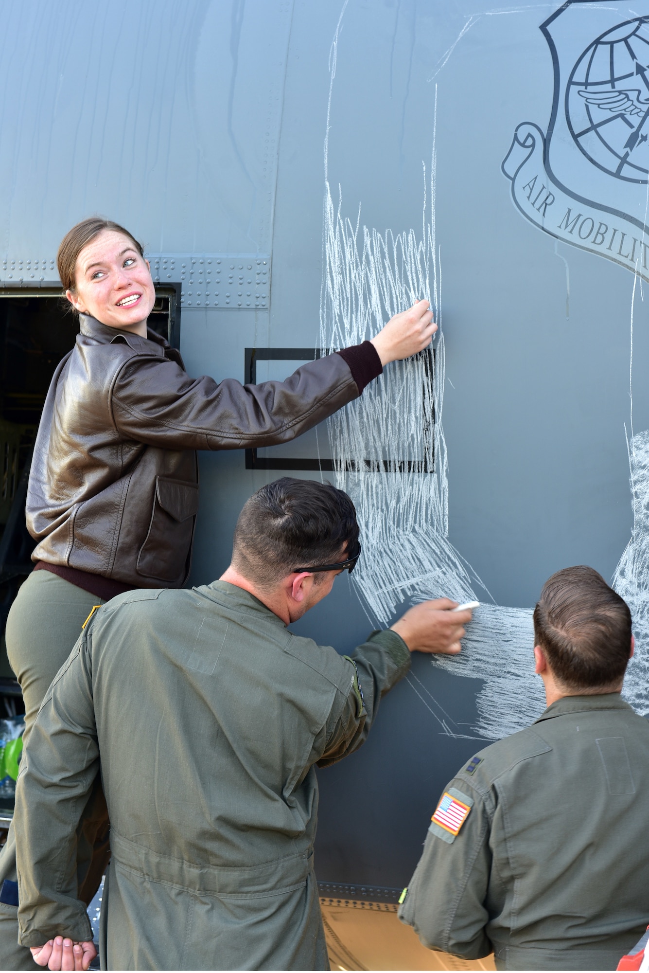 An Airman draws with chalk on the side of a C-130J