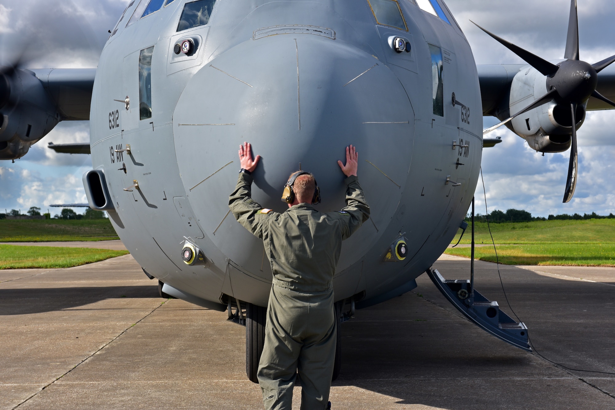 An Airman hugs the nose of a C-130J