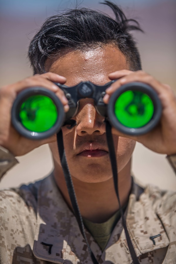 U.S. Marine Pfc. Loeurenz Bunla, a forward observer with N Battery, 5th Battalion, 14th Marine Regiment, 4th Marine Division looks through binoculars at Observation Post Left during Integrated Training Exercise 4-19 at Marine Corps Air Ground Combat Center, Twentynine Palms, Calif., June 8, 2019. The ITX force includes each of the Marine Air-Ground Task Force’s subordinate elements who work together in the application of combined-arms maneuver warfare during the exercise. (U.S. Marine Corps photo by Lance Cpl. Preston L. Morris)