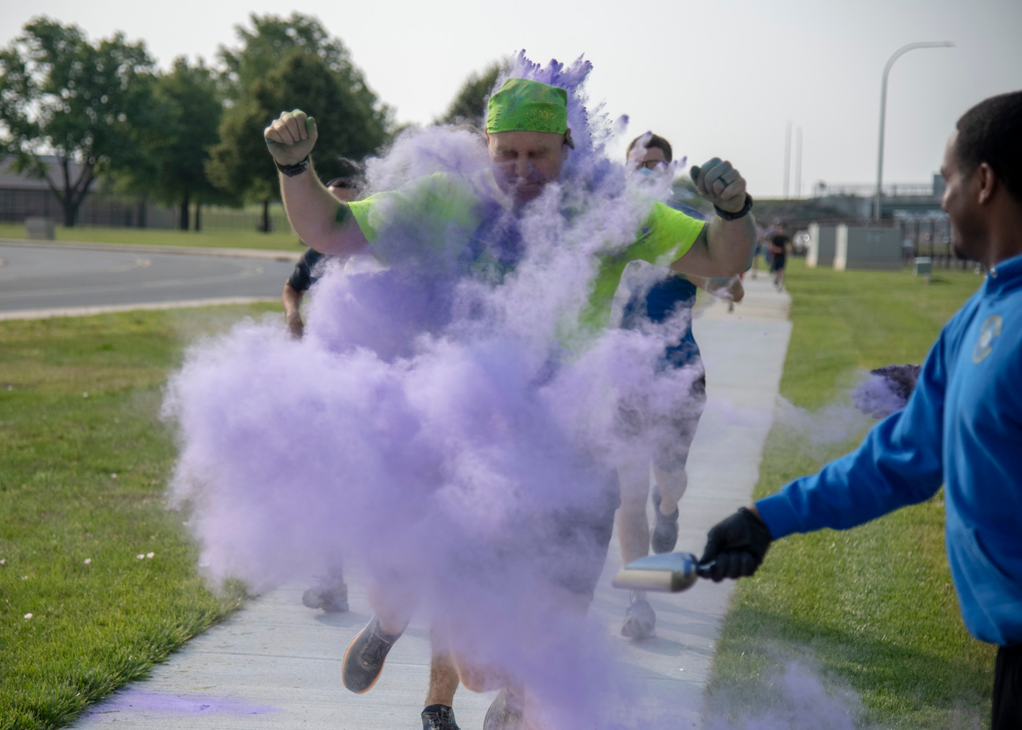 Volunteers throw purple color powder at runners during the 2019 Sexual Assault Prevention and Response Color Run June 5, 2019, at Dover Air Force Base, Del. Volunteers waited at several stations along the course to cover the passing runners in bright color powder. (U.S. Air Force photo by Staff Sgt. Esteban Esquivel)