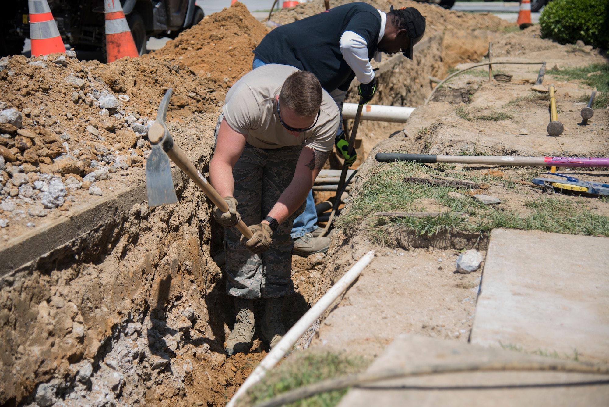Airman 1st Class Keifer Donovan, 436th Civil
Engineer Squadron pavement and equipment
apprentice, swings a pickaxe to break up rocks
and dirt June 3, 2019, at Dover Air Force Base,
Del. The trench is being created in order to
install a French drain, which is a perforated
pipe that will divert water away from the main
gate entry control point building. (U.S. Air Force
photo by Airman 1st Class Jonathan Harding)