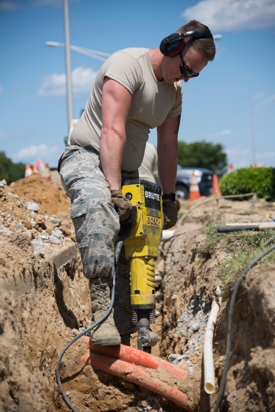 Airman 1st Class Keifer Donovan, 436th Civil
Engineer Squadron pavement and equipment apprentice, uses a jackhammer to break up
rocky terrain near the main gate for a French
drain installation project June 3, 2019, at Dover
Air Force Base, Del. With various power and gas
lines buried around the dig site, the majority of
digging was accomplished using a pickaxe and
shovel. (U.S. Air Force photo by Airman 1st
Class Jonathan Harding).