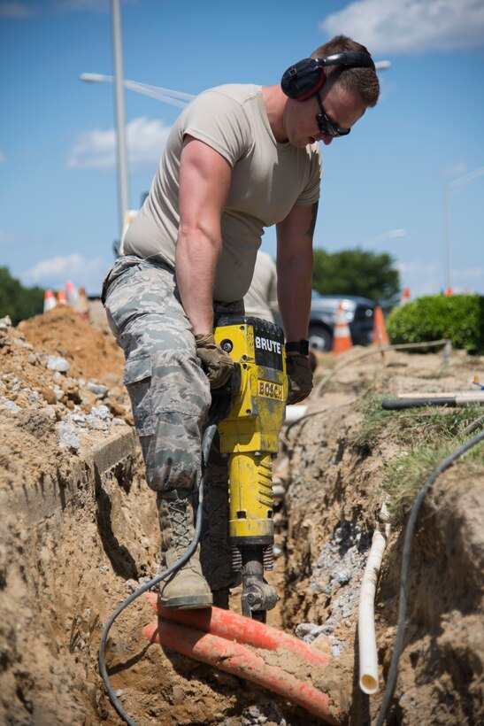 Airman 1st Class Keifer Donovan, 436th Civil
Engineer Squadron pavement and equipment apprentice, uses a jackhammer to break up
rocky terrain near the main gate for a French
drain installation project June 3, 2019, at Dover
Air Force Base, Del. With various power and gas
lines buried around the dig site, the majority of
digging was accomplished using a pickaxe and
shovel. (U.S. Air Force photo by Airman 1st
Class Jonathan Harding).