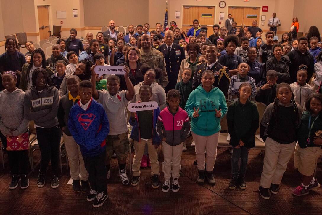 A large group of children  poses in an auditorium.