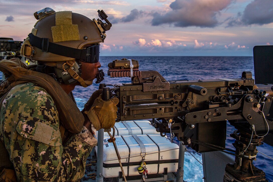 A sailor fires a gun on a patrol boat.