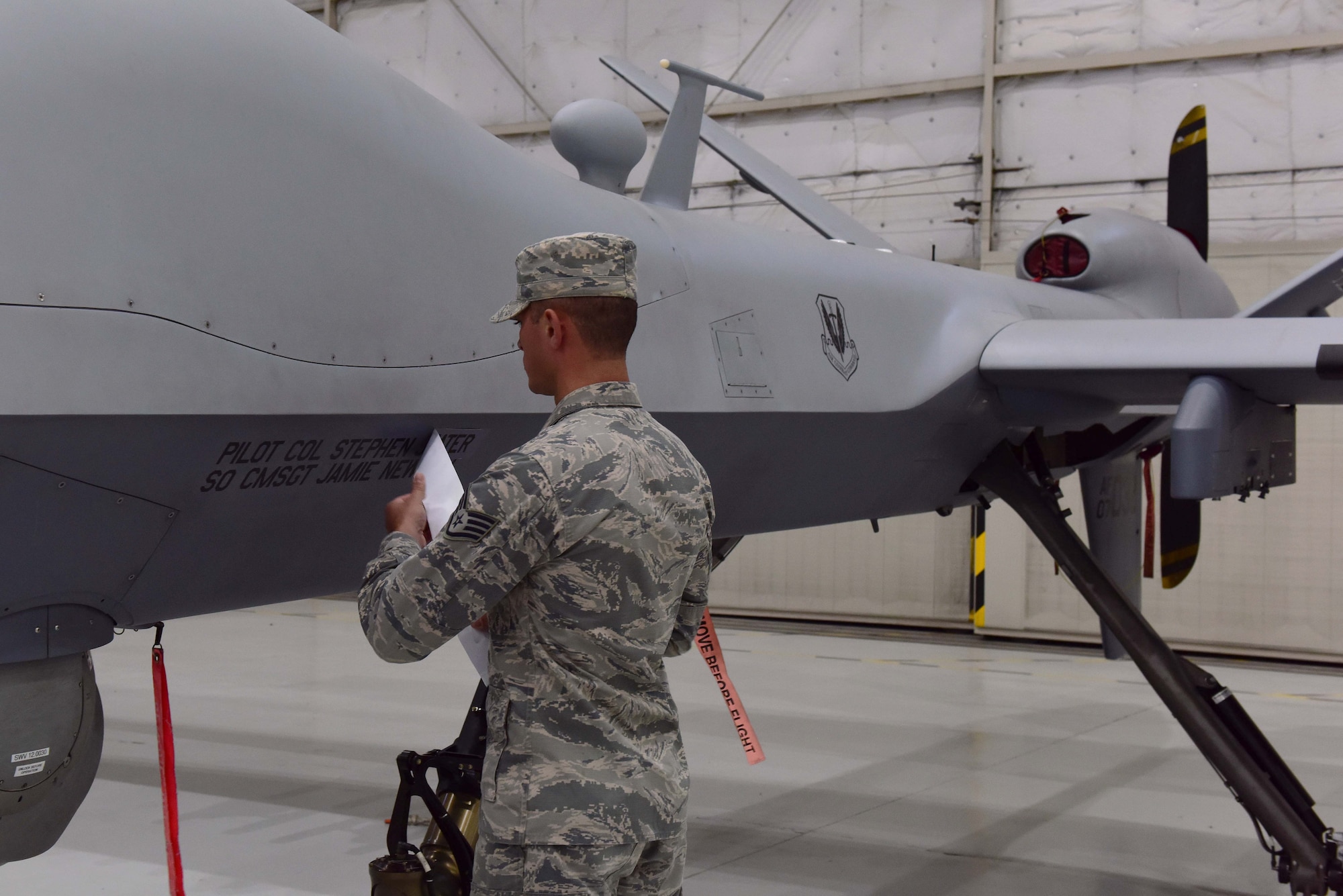 Staff Sgt. Justin, 432nd Aircraft Maintenance Squadron, unveils the name of the incoming 432nd Wing/432nd Air Expeditionary Wing commander on an MQ-9 Reaper during the 432nd WG change of command ceremony at Creech Air Force Base, Nevada, June 7, 2019. During the event, Col. Stephen Jones assumed command of the award-winning Remotely Piloted Aircraft wing from Col. Julian Cheater. (U.S. Air Force photo by Airman 1st Class Haley Stevens)