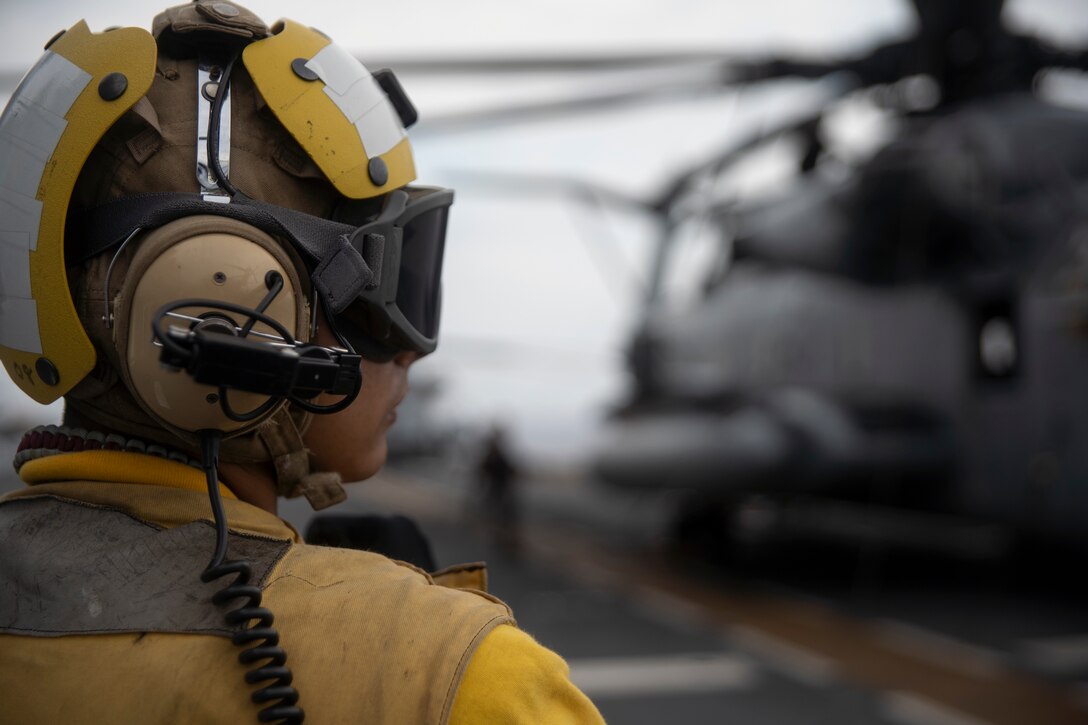 A flight deck crewmember watches after a CH-53E Super Stallion with Marine Medium Tiltrotor Squadron 265 (Reinforced) lands aboard the amphibious assault ship USS Wasp (LHD 1) during flight operations while underway in the Philippine Sea, June 4, 2019. The 31st Marine Expeditionary Unit, the Marine Corps’ only continuously forward-deployed MEU, provides a flexible and lethal force ready to perform a wide range of military operations as the premier crisis response force in the Indo-Pacific region. (Official U.S. Marine Corps photo by Lance Cpl. Brennan Priest)