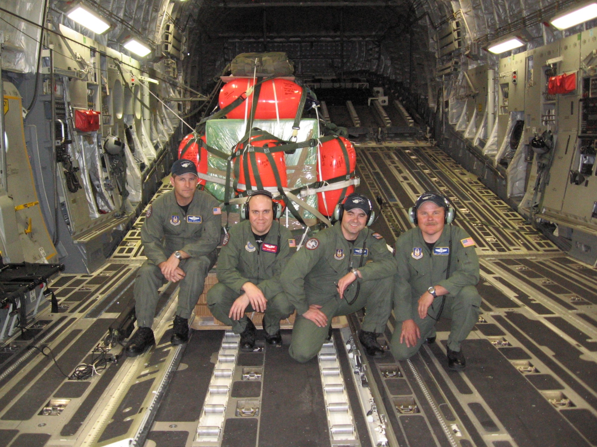 Chief Master Sgt. James Masura Jr., 313th Airlift Squadron loadmaster, and 304th Expeditionary Air Squadron loadmasters, pause for a photo with the airdrop equipment to aid a fishing vessel broken down in the Antarctic. Argos Georgia had suffered serious engine failure while heading south in the Ross Sea, leaving it without propulsion and drifting with the ice Jan. 4, 2008, according to an article released by PACAF Public Affairs. The vessel needed critical engine repair parts airdropped to them so crews could fix damaged caused by navigating the icy waters. (Courtesy photo)