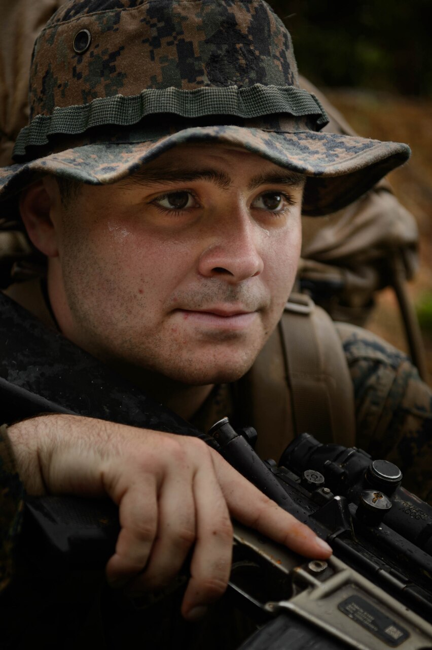 A close up of a Sailors face holding a rifle.