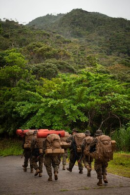 A group of sailors walks down a road with packs on.